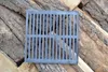 A square cast iron grate lies on a pile of logs. Anteprima dell’immagine prodotto