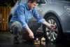 A man is using a tire sealant kit to repair a car tire. Produktbild-Vorschau