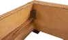Close-up view of the corner of a bed frame, showing the woven material and internal wooden structure with a metal bracket. Produktbild-Vorschau