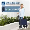 A woman is holding a folded blue cart while standing outdoors with greenery in the background. An overlay provides product information. Produktbild-Vorschau