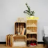 A collection of wooden crates arranged as shelving, decorated with books, a plant, and a neon sign. Produktbild-Vorschau