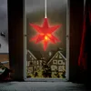 A red star-shaped LED light hangs in a window, illuminating a snowy scene with houses and a Christmas tree outside. Anteprima dell’immagine prodotto
