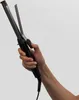 A hand holding a curling iron against a white background. Náhled obrázku produktu