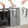 Three recycling bags are shown side-by-side, with hands placing items into each bag. The bags are black, gray, and white, and each has a recycling symbol with icons representing different types of waste. Produktbild-Vorschau
