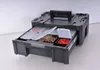 A black tool box with a handle and a drawer pulled out, showing compartments with various hardware items. Voir les images du produit