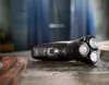 A wet electric shaver is lying on a textured surface, possibly a bathroom counter, with water droplets visible. Podgląd zdjęcia produktu