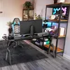 A gaming setup with a desk, chair, and shelving unit in a room. Produktbild-Vorschau