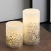 Two LED candles with glitter accents are placed on a wooden surface. Produktbild-Vorschau