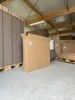 A large cardboard box is shown in a warehouse setting, with stacks of cardboard in the background. Produktbild-Vorschau