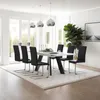 A modern dining room with a white table and black chairs, illuminated by pendant lights. Voir les images du produit
