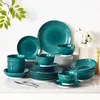 A collection of teal-colored ceramic dinnerware with a spiral pattern, arranged on a light gray surface against a white background. Green leaves are visible in the upper left corner, and white flowers in a vase are in the upper right. Produktbild-Vorschau