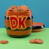 A Donkey Kong themed cookie jar filled with cookies, placed on a green surface with a blue background. A lid is placed next to the jar. Produktbild-Vorschau