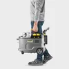 A person is carrying a Kärcher Puzzi 9/1 BP Waschsauger. Produktbild-Vorschau