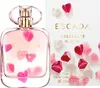 A bottle of Escada Celebrate N.O.W. Eau de Parfum and its packaging are displayed against a white background, decorated with pink and white heart-shaped petals. Produktbild-Vorschau