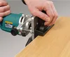 A person is using a router on a wooden surface. Voir les images du produit
