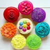A collection of colorful cupcakes arranged on a white wooden surface. Náhled obrázku produktu