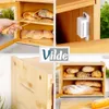 A collage of images showing a bamboo bread box filled with various types of bread. One image shows a hand using tongs to pick up bread from the box, another shows a close-up of the bread box's magnetic latch, and the bottom images show the bread box from t Náhled obrázku produktu