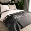 A bed with a duvet cover featuring a dark floral pattern and two pillows. Produktbild-Vorschau