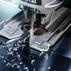 A close-up shot of a jigsaw cutting through a dark surface, with metal shavings scattered around. Voir les images du produit