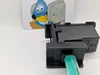 A black ink cartridge cleaning kit with a green syringe is shown in the foreground, with a cartoon image of a water drop character using a computer in the background. Produktbild-Vorschau