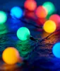 A close-up of a string of colorful LED lights on a dark, textured surface. Produktbild-Vorschau