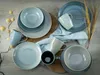 A collection of blue and gray ceramic dishes and mugs arranged on a wooden surface with some dried decorative elements. Náhľad obrázku produktu