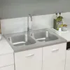 A stainless steel double sink with a faucet, set into a white countertop and cabinets, with some kitchen items in the background. Náhled obrázku produktu