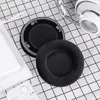 A pair of black ear pads for headphones are laid out on a black and white checkered cloth, next to a white smartphone and a pair of white earbuds. Náhľad obrázku produktu