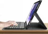 A tablet with a keyboard case is shown on a wooden surface, with hands typing on the keyboard. Podgląd zdjęcia produktu