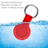 A red silicone AirTag case is partially submerged in water, with water splashing around it. A silver keyring is attached to the case. Produktbild-Vorschau