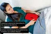 A woman is lying on a couch with a red electric hot water bottle on her abdomen. Produktbild-Vorschau