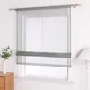 A sheer Roman blind with a gray band is installed on a window. Produktbild-Vorschau