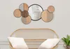 A wall mirror with circular wooden elements is displayed above a rattan sofa with white cushions. Produktbild-Vorschau