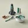 A collection of kitchen utensils and measuring cups are arranged on a light green surface. Produktbild-Vorschau