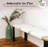 A corner of a room with a bench and a vase of flowers. Produktbild-Vorschau