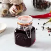 A small Kilner jar filled with a dark red liquid, placed on a marble surface. In the background, there are garlic bulbs, peppercorns, and chili peppers. Anteprima dell’immagine prodotto