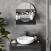 A modern bathroom vanity with a round sink and a circular mirror above it, featuring various toiletries and accessories. Produktbild-Vorschau
