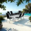 An outdoor dining set with a table and chairs is set up on a patio overlooking the ocean, with a swimming pool in the background. Voir les images du produit