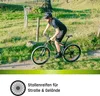 A person riding a mountain bike on a dirt path surrounded by grass and trees. Produktbild-Vorschau