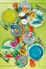 A collection of tropical-themed plates and bowls arranged on a green wooden surface, with some fruit and coconut halves. Produktbild-Vorschau