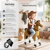 A young girl dressed as a cowboy rides a toy horse with wheels indoors. Náhled obrázku produktu