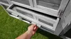 A hand is shown pulling out a tray from a chicken coop. Produktbild-Vorschau