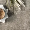 A close-up overhead view of a beige carpet with a wooden bowl and some decorative grass on top. Produktbild-Vorschau