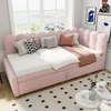 A pink upholstered daybed with a scalloped headboard is set up in a bright room with a large window. Pillows and a throw blanket are arranged on the bed, and two small white side tables are in the foreground. Podgląd zdjęcia produktu