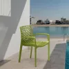 A green chair is placed on a patio next to a swimming pool, with a body of water and buildings in the background. Produktbild-Vorschau