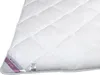 A close-up view of a white quilted blanket. Produktbild-Vorschau