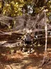 A Halloween decoration scene in a wooded area with large fake spiders and cobwebs. Produktbild-Vorschau