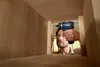 A man is using a Bosch cordless drill inside a wooden structure, possibly a cabinet or shelf. Náhled obrázku produktu