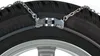 A close-up of a car tire with snow chains attached. Produktbild-Vorschau