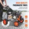 A person is holding the handle of a pressure washer with pneumatic tires. The background shows a body of water and buildings. Produktbild-Vorschau